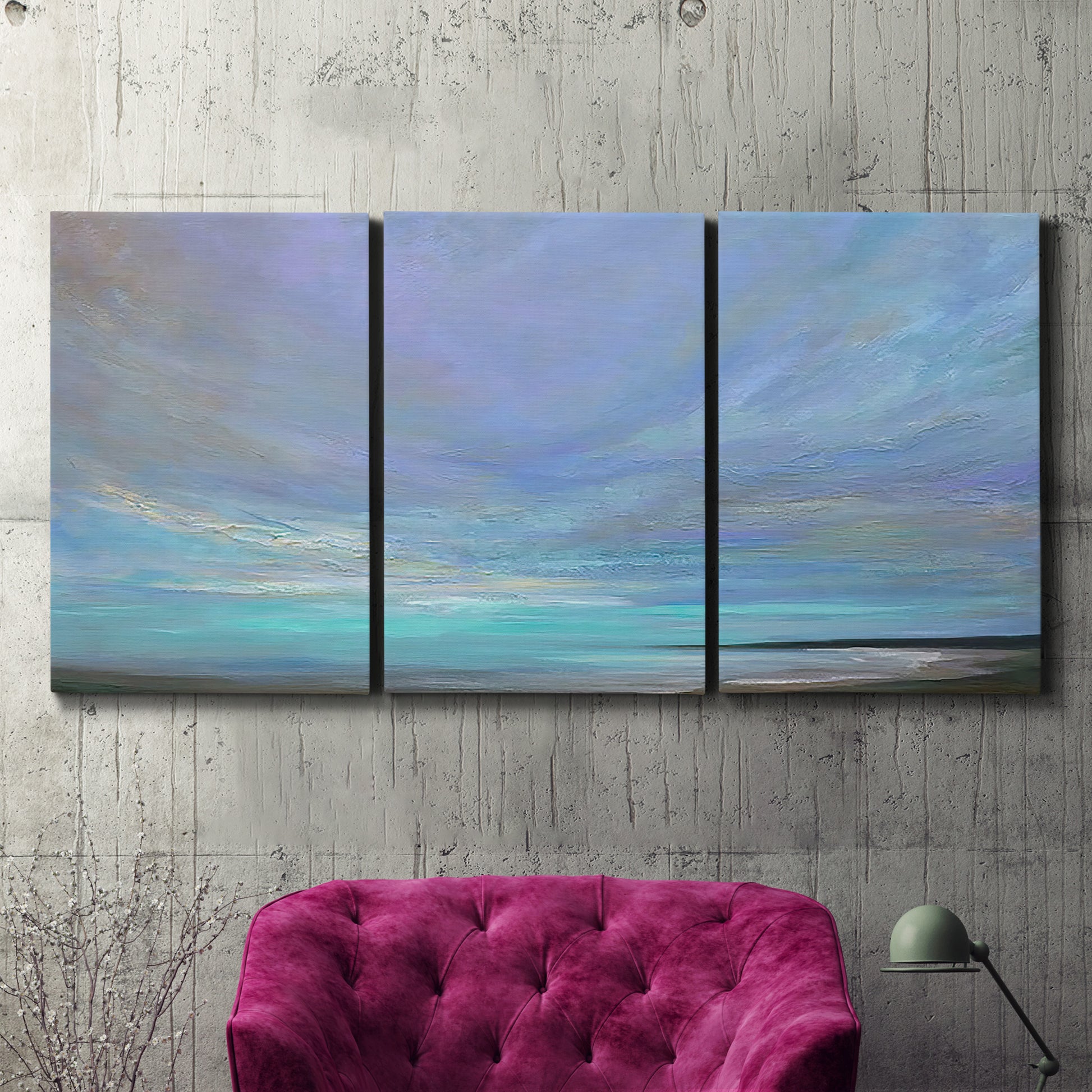 Three-panel canvas wall art featuring coastal shoreline with gentle surf, displayed in a living room above a suede accent chair.