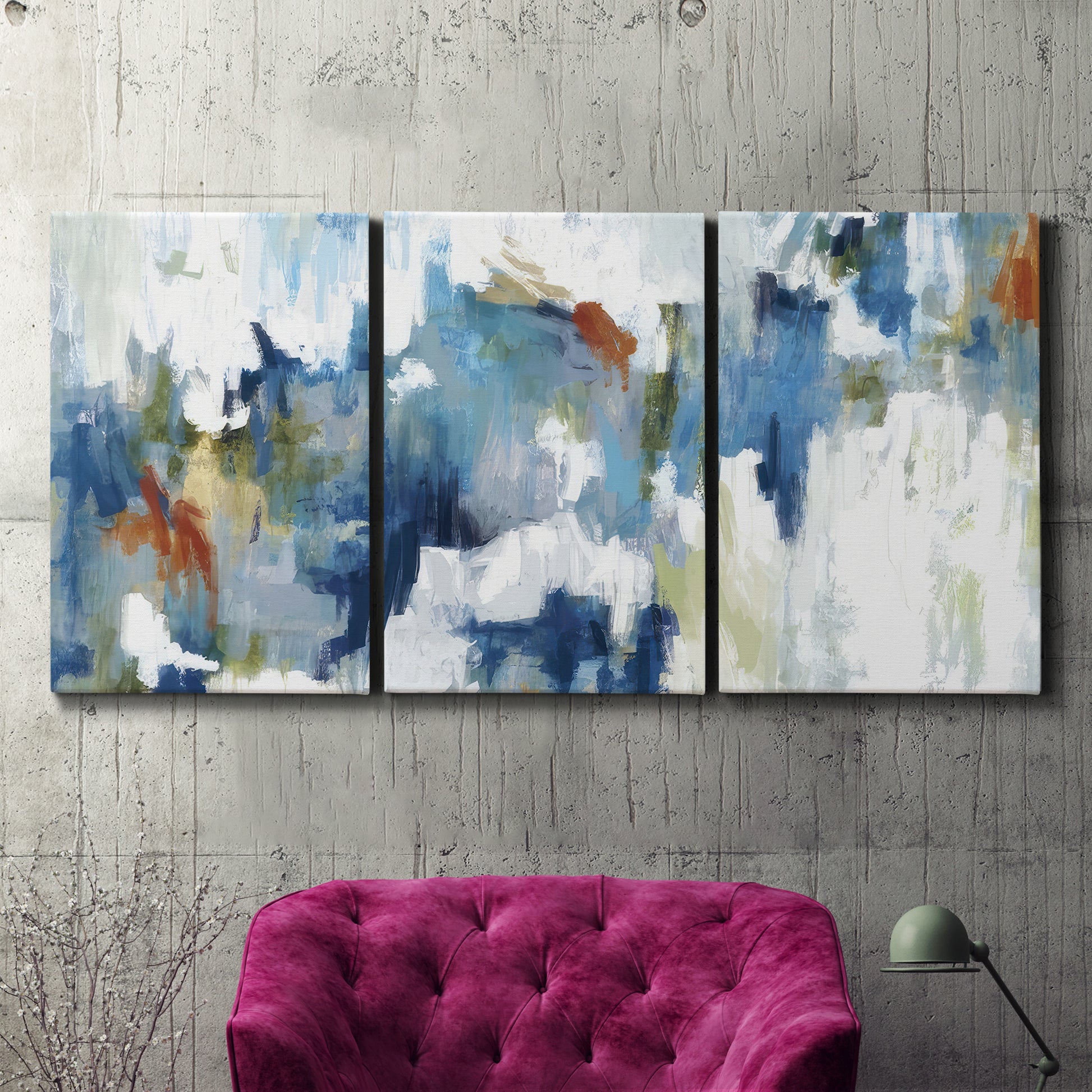 Three-panel canvas wall art featuring flowing abstract color movement, displayed in a living room above a suede accent chair.