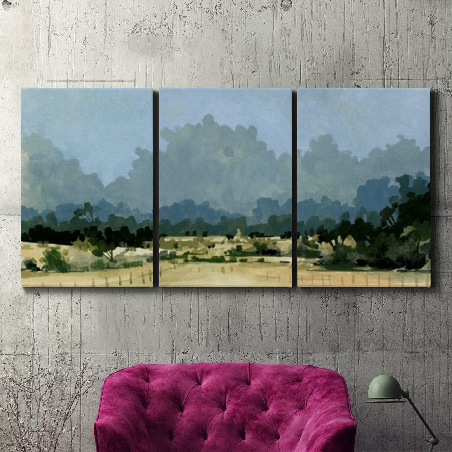 Three-panel canvas wall art featuring rural farmland landscape in watercolor, displayed in a living room above a suede accent chair.