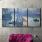 Three-panel canvas wall art featuring sailboats racing on river, displayed in a living room above a suede accent chair.
