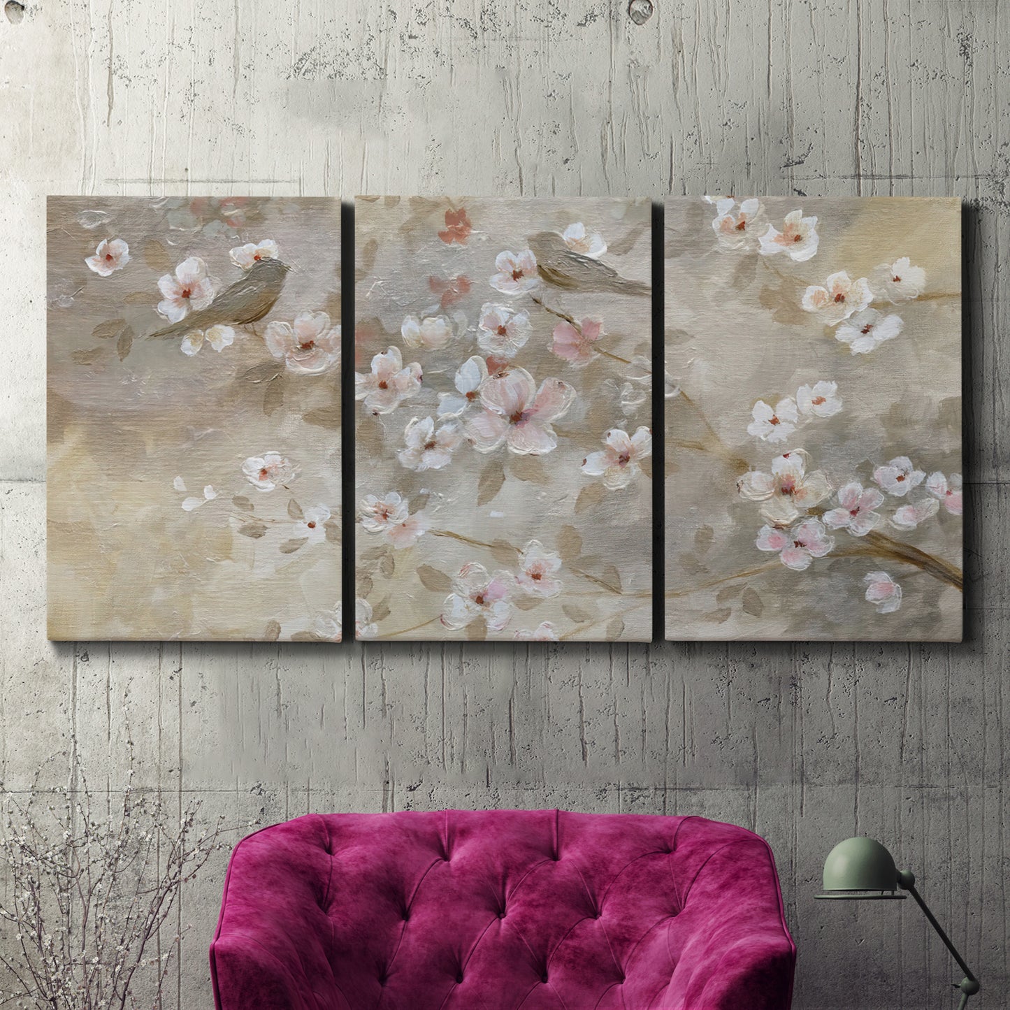 Three-panel canvas wall art featuring early spring blossoms in soft tones, displayed in a living room above a suede accent chair.