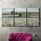 Three-panel canvas wall art featuring vintage poppy filled valley, displayed in a living room above a suede accent chair.