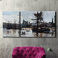 Three-panel canvas wall art featuring harbor scene with boats and quays, displayed in a living room above a suede accent chair.
