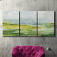 Three-panel canvas wall art featuring lowland wetlands with reflective water, displayed in a living room above a suede accent chair.