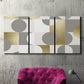 Three-panel canvas wall art featuring geometric gold abstract reflections, displayed in a living room above a suede accent chair.