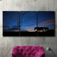 Three-panel canvas wall art featuring resting animals in open field, displayed in a living room above a suede accent chair.