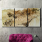 Three-panel canvas wall art featuring muted abstract with metallic gold accents, displayed in a living room above a suede accent chair.