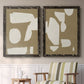 Set of two black barnwood framed canvas prints depicting two bold minimalist shape abstracts featuring irregular white cutout-like shapes on taupe grounds above a sideboard in a cozy sitting room.