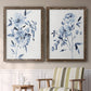 Set of two walnut barnwood framed canvas prints depicting two expressive watercolor botanical paintings featuring loose blue flowers and leafy branches above a sideboard in a cozy sitting room.