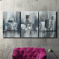 Three-panel canvas wall art featuring urban cityscape rendered in blue tones, displayed in a living room above a suede accent chair.