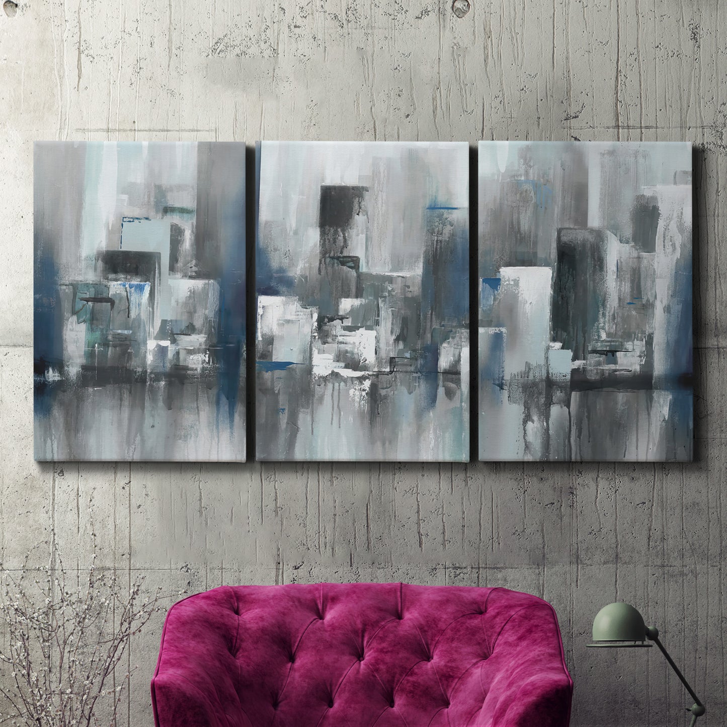 Three-panel canvas wall art featuring urban cityscape rendered in blue tones, displayed in a living room above a suede accent chair.