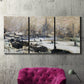 Three-panel canvas wall art featuring snowy village road in winter, displayed in a living room above a suede accent chair.