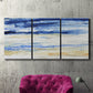 Three-panel canvas wall art featuring turbulent abstract ocean wave motion, displayed in a living room above a suede accent chair.