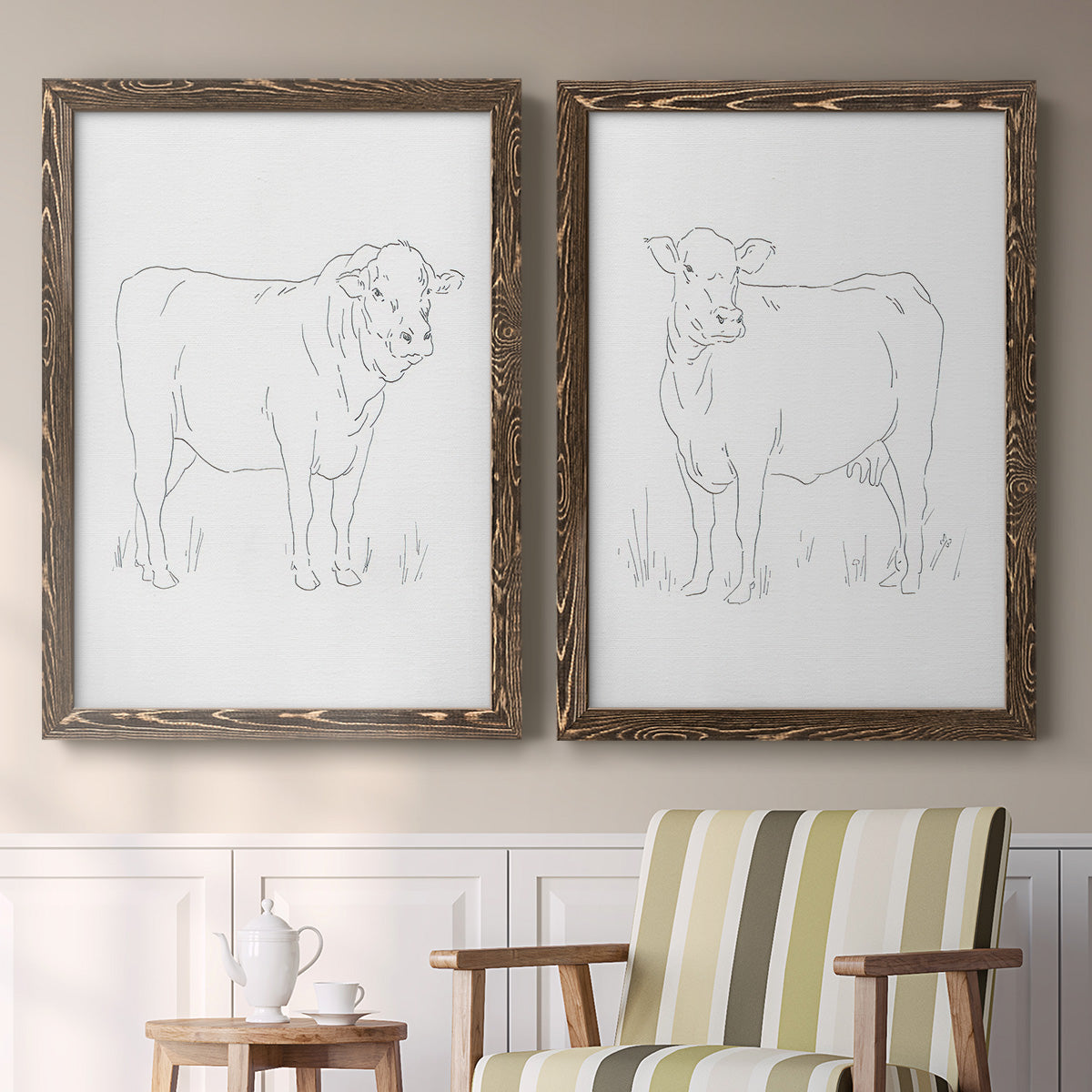 Set of two walnut barnwood framed canvas prints depicting two minimalist livestock sketches featuring simple contour drawings of standing cows above a sideboard in a cozy sitting room.