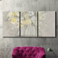 Three-panel canvas wall art featuring vintage floral abstract composition, displayed in a living room above a suede accent chair.