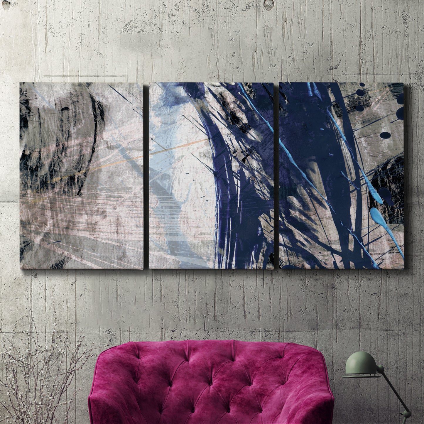 Three-panel canvas wall art featuring layered blue abstract texture, displayed in a living room above a suede accent chair.