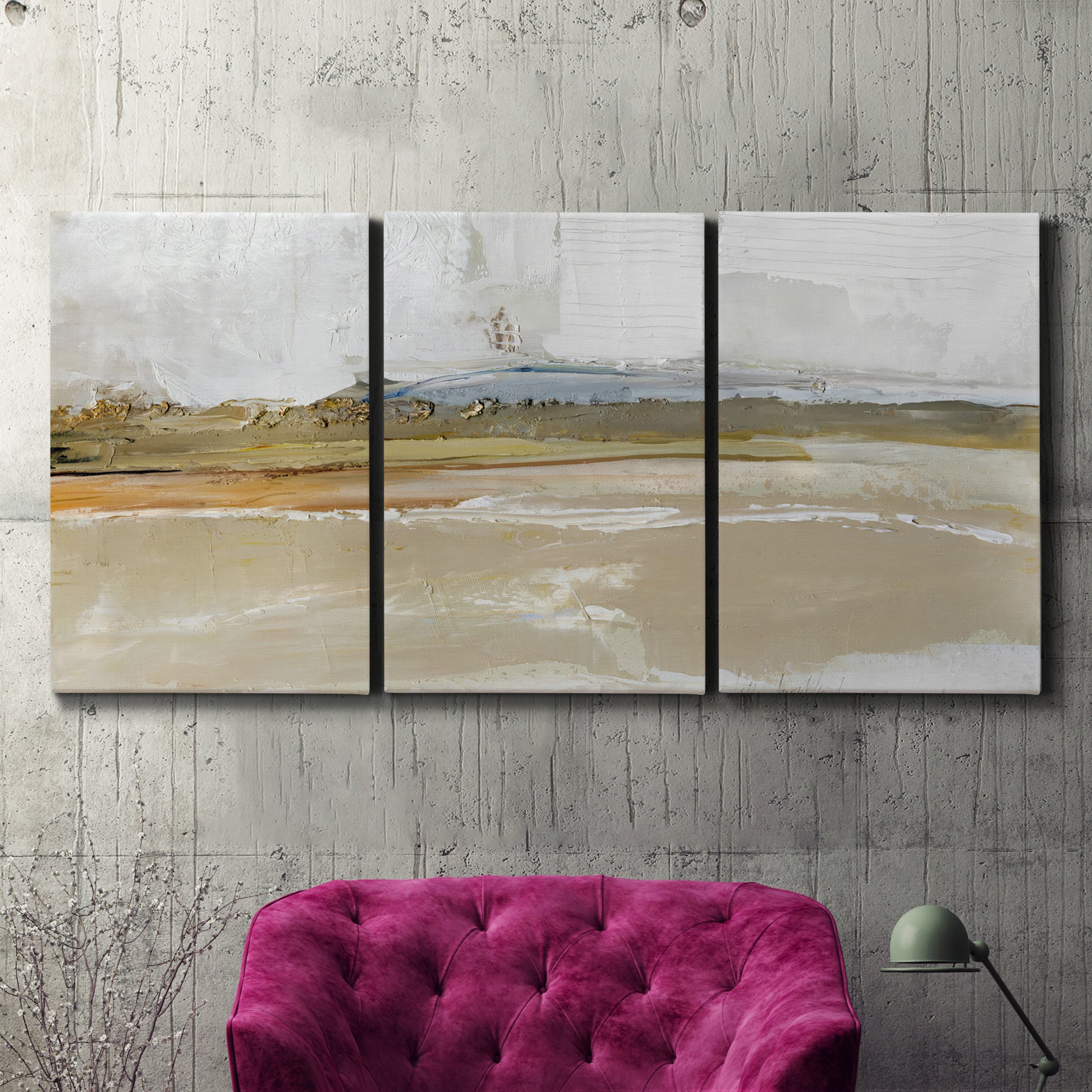 Three-panel canvas wall art featuring golden hour light over landscape, displayed in a living room above a suede accent chair.