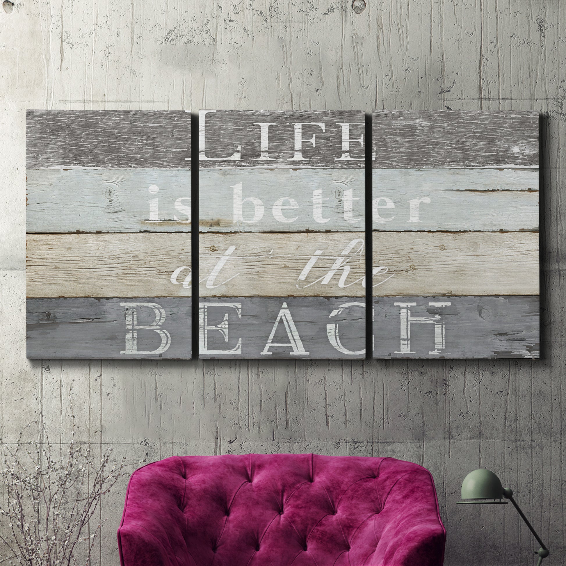 Three-panel canvas wall art featuring beach themed typography design, displayed in a living room above a suede accent chair.