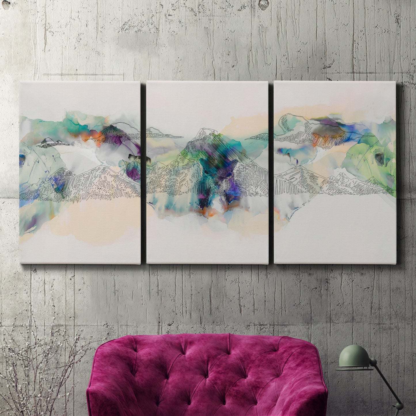 Three-panel canvas wall art featuring abstract mountain range watercolor, displayed in a living room above a suede accent chair.