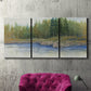 Three-panel canvas wall art featuring riverbank landscape with trees, displayed in a living room above a suede accent chair.