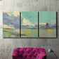 Three-panel canvas wall art featuring road stretching through open countryside, displayed in a living room above a suede accent chair.