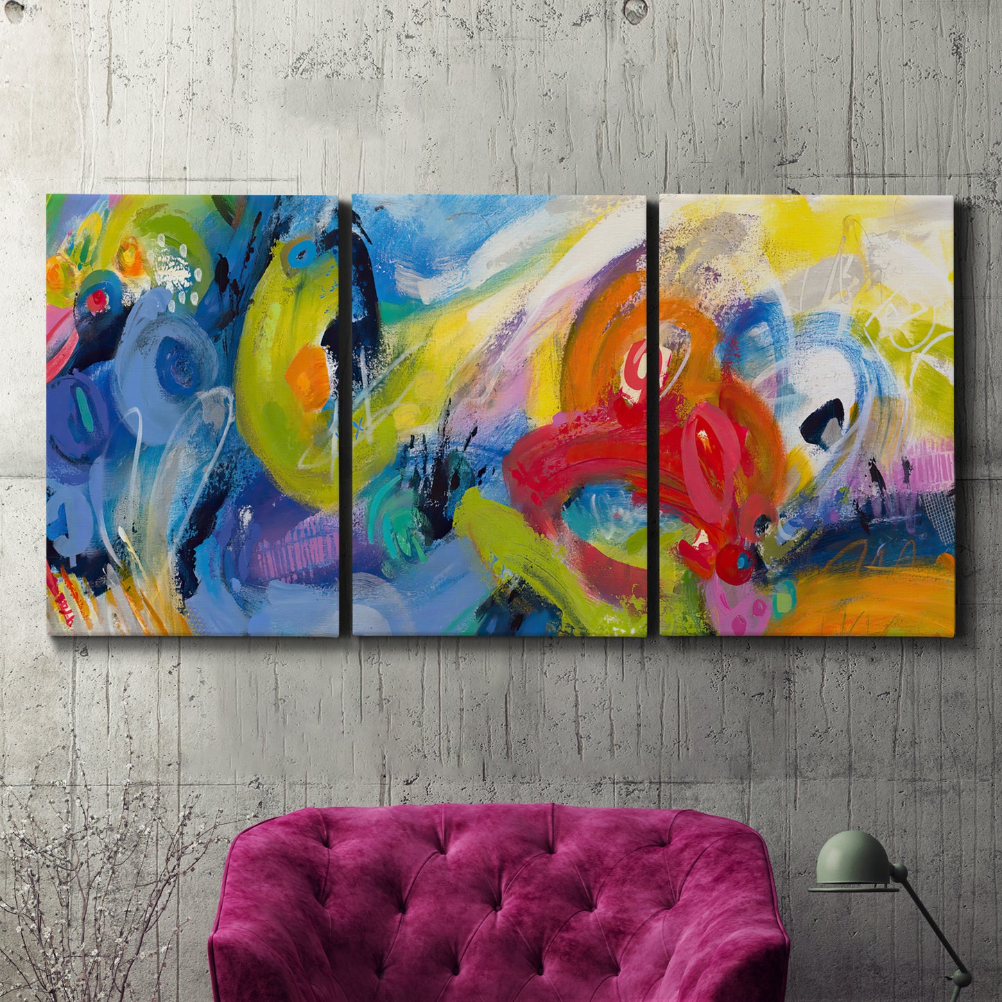 Three-panel canvas wall art featuring colorful abstract racing forms, displayed in a living room above a suede accent chair.