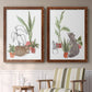 Set of two maple barnwood framed canvas prints depicting two whimsical botanical animal illustrations featuring cats tucked among collections of potted houseplants above a sideboard in a cozy sitting room.