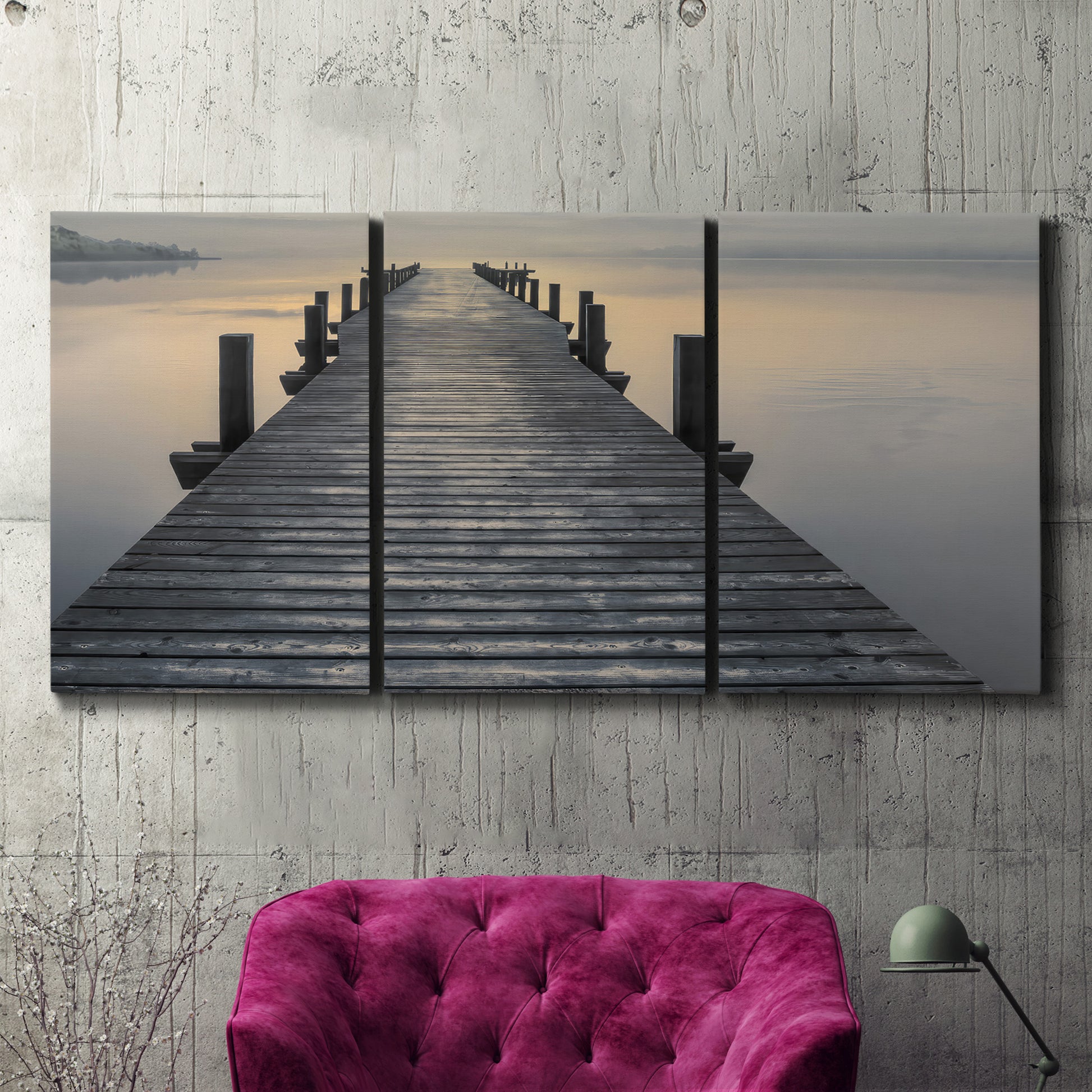 Three-panel canvas wall art featuring sunset over water photograph, displayed in a living room above a suede accent chair.