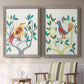 Set of two gray barnwood framed canvas prints depicting two modern folk-art bird illustrations featuring stylized colorful birds perched among leafy branches above a sideboard in a cozy sitting room.