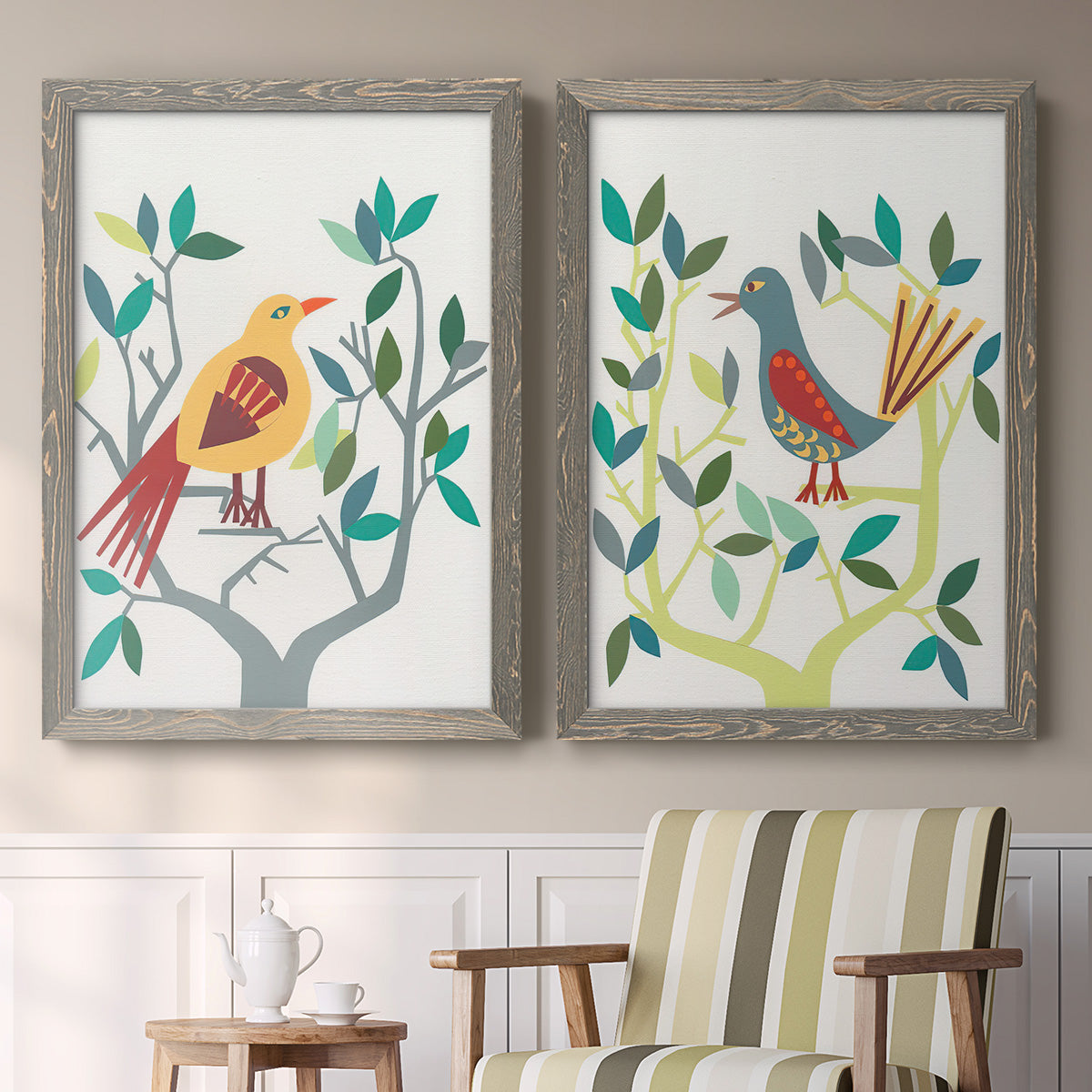 Set of two gray barnwood framed canvas prints depicting two modern folk-art bird illustrations featuring stylized colorful birds perched among leafy branches above a sideboard in a cozy sitting room.