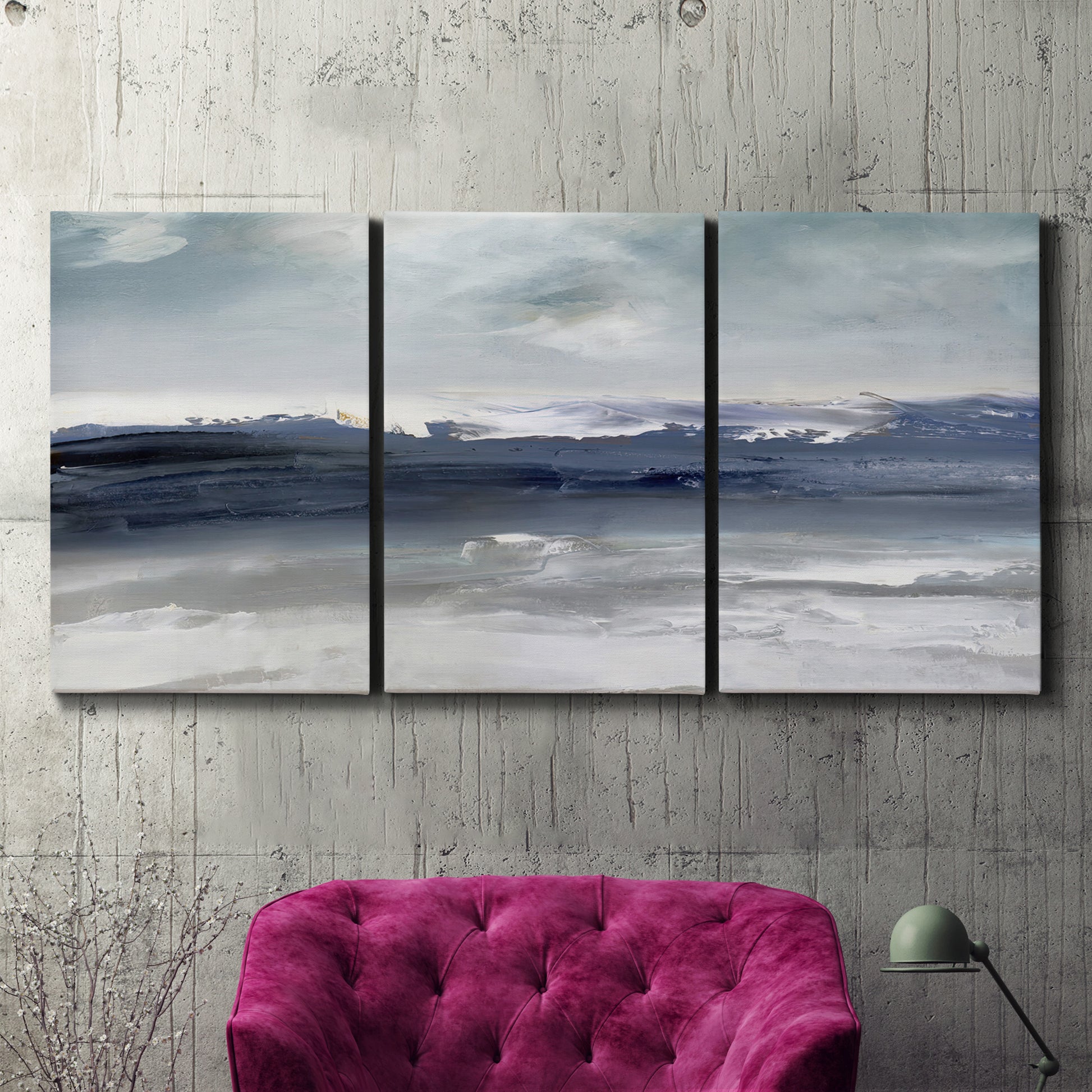Three-panel canvas wall art featuring abstract coastal tones and movement, displayed in a living room above a suede accent chair.