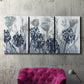 Three-panel canvas wall art featuring indigo floral abstraction, displayed in a living room above a suede accent chair.