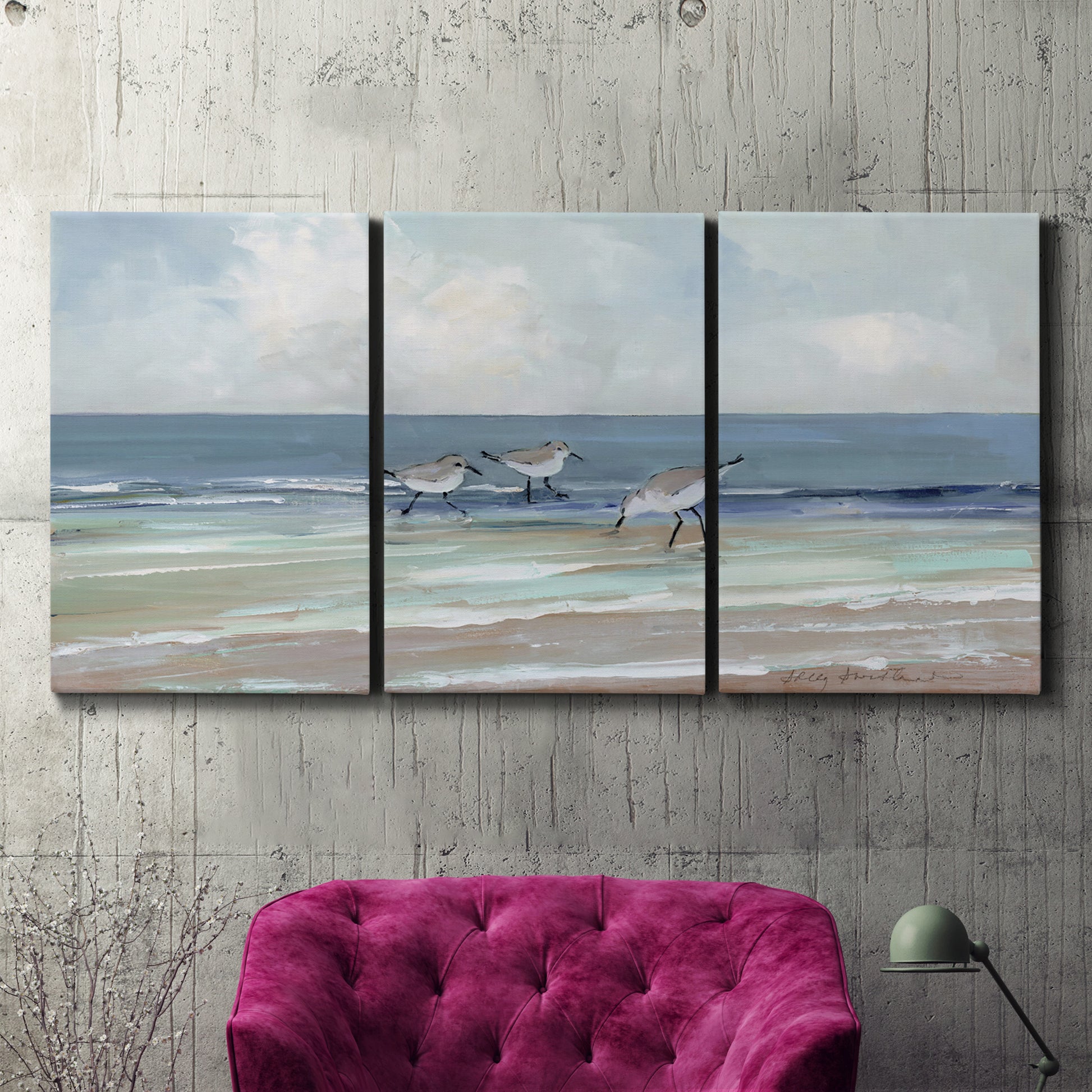 Three-panel canvas wall art featuring shore birds searching along beach, displayed in a living room above a suede accent chair.