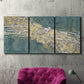 Three-panel canvas wall art featuring soft abstract wind movement, displayed in a living room above a suede accent chair.