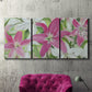 Three-panel canvas wall art featuring pink and white lilies in bloom, displayed in a living room above a suede accent chair.