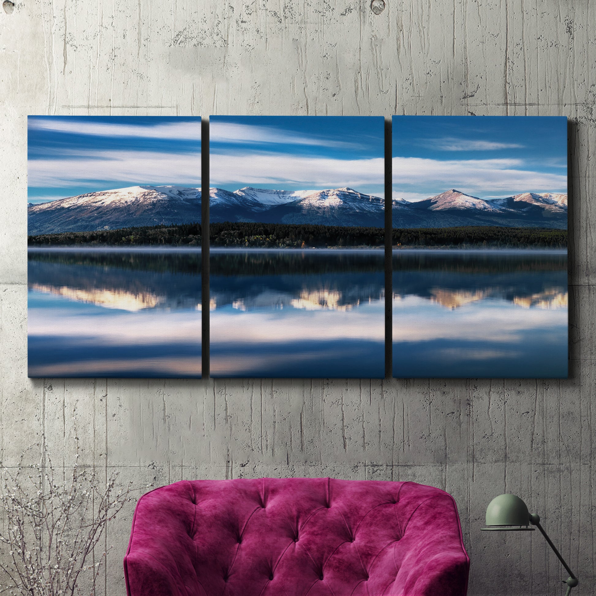 Three-panel canvas wall art featuring calm lake beneath mountains photograph, displayed in a living room above a suede accent chair.