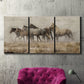 Three-panel canvas wall art featuring wild horses roaming open terrain, displayed in a living room above a suede accent chair.