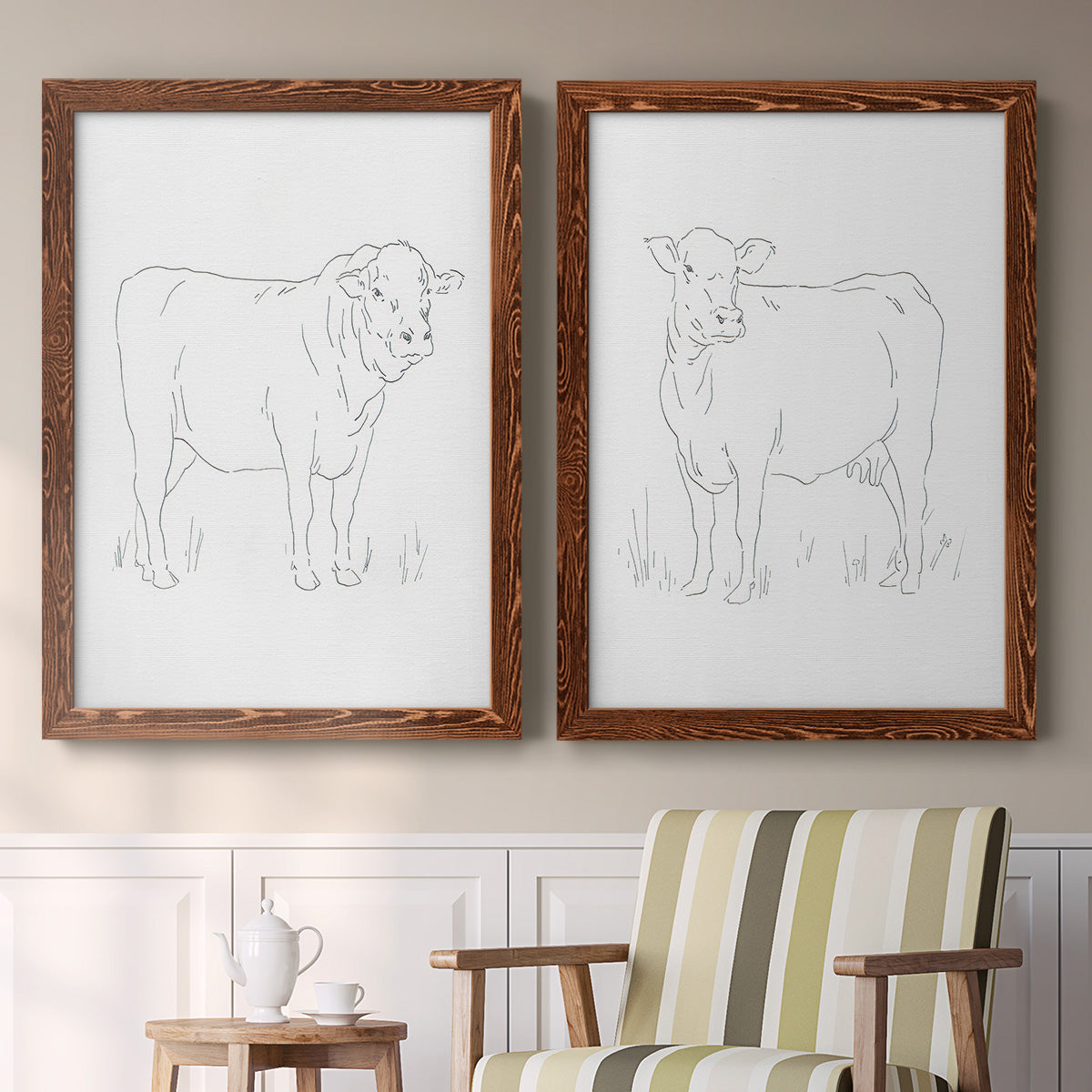 Set of two maple barnwood framed canvas prints depicting two minimalist livestock sketches featuring simple contour drawings of standing cows above a sideboard in a cozy sitting room.