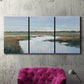 Three-panel canvas wall art featuring coastal plain meeting open water, displayed in a living room above a suede accent chair.