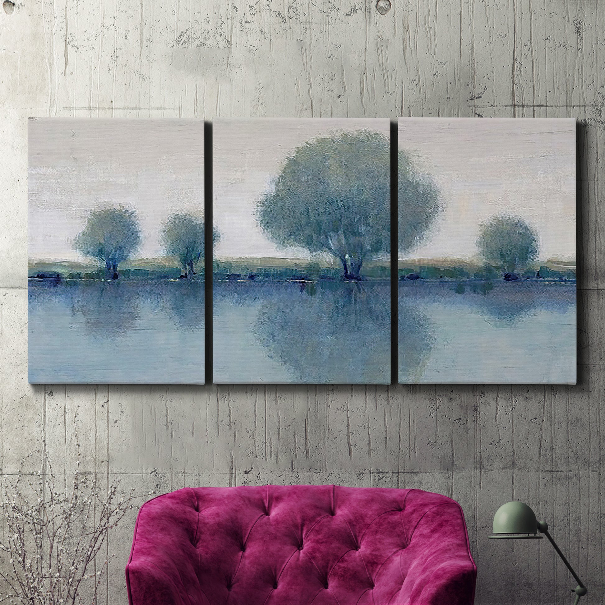 Three-panel canvas wall art featuring calm afternoon river reflection, displayed in a living room above a suede accent chair.
