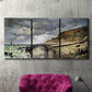 Three-panel canvas wall art featuring sunset beach with glowing sky, displayed in a living room above a suede accent chair.
