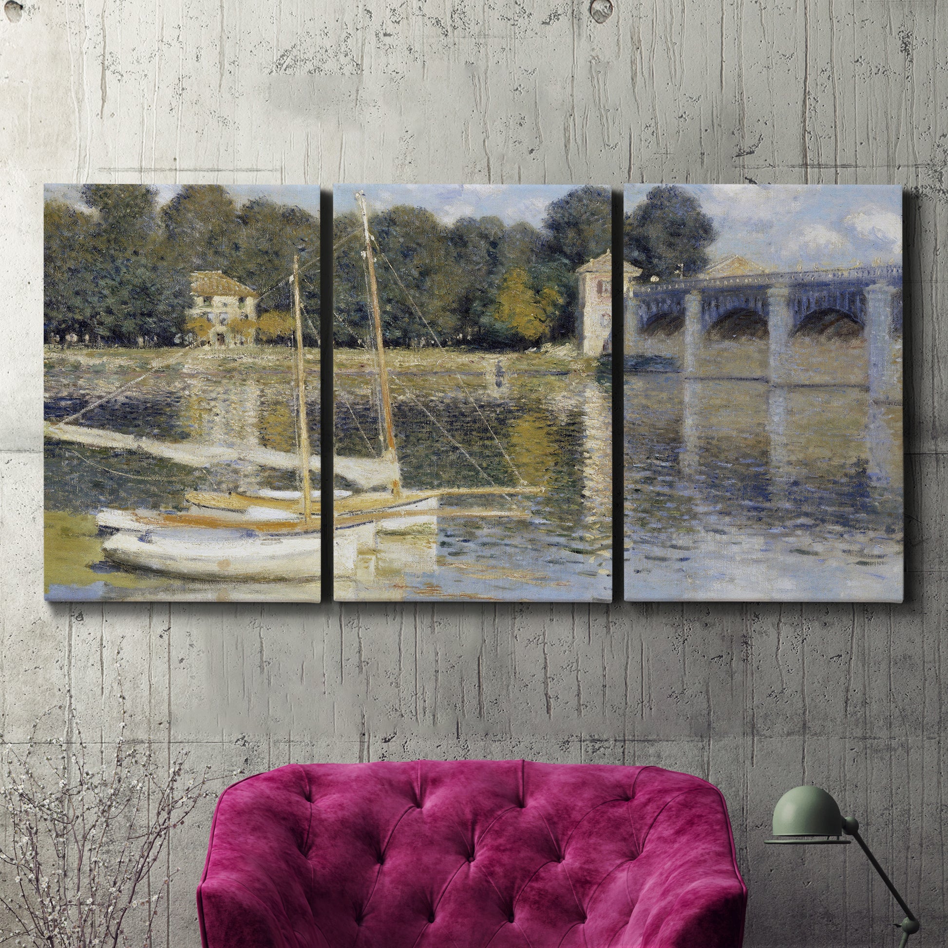 Three-panel canvas wall art featuring bridge crossing broad river, displayed in a living room above a suede accent chair.