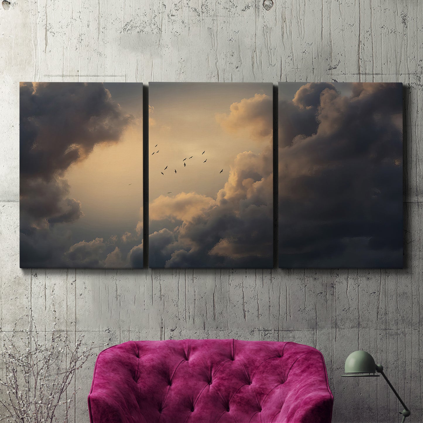 Three-panel canvas wall art featuring surreal floating figures above landscape, displayed in a living room above a suede accent chair.