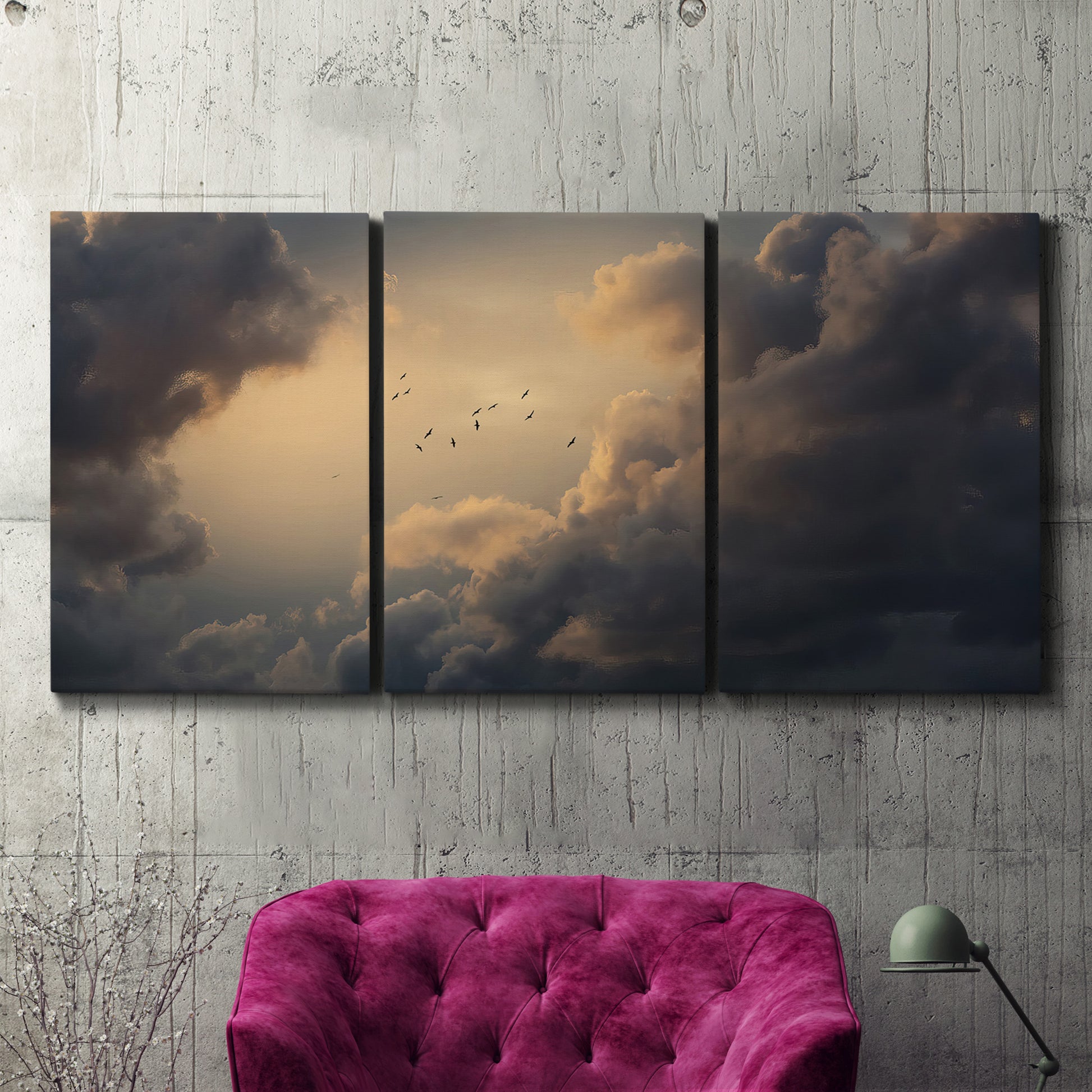 Three-panel canvas wall art featuring surreal floating figures above landscape, displayed in a living room above a suede accent chair.