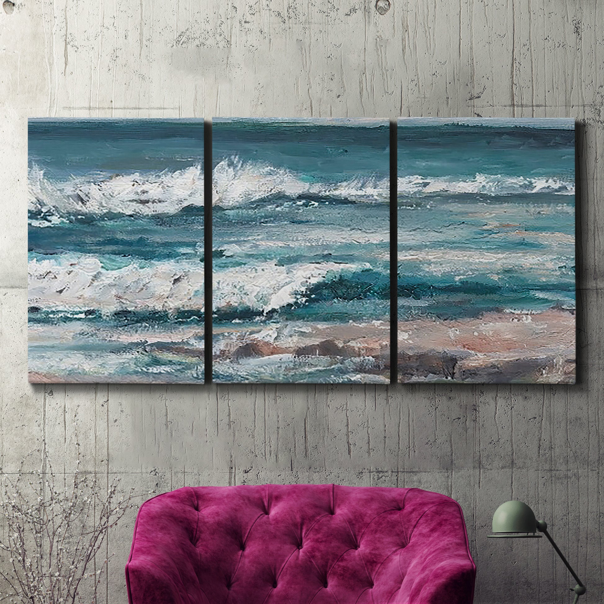Three-panel canvas wall art featuring crashing ocean waves along shoreline, displayed in a living room above a suede accent chair.