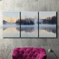 Three-panel canvas wall art featuring misty water landscape photograph, displayed in a living room above a suede accent chair.