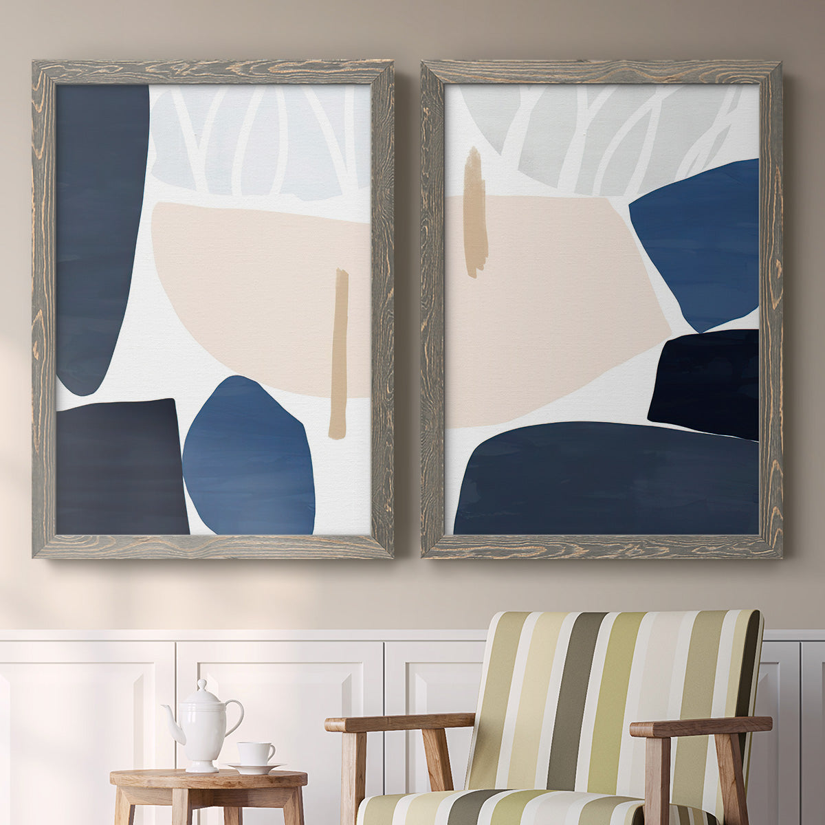 Set of two gray barnwood framed canvas prints depicting two minimalist color-block abstracts featuring large navy cream and beige organic geometric shapes above a sideboard in a cozy sitting room.