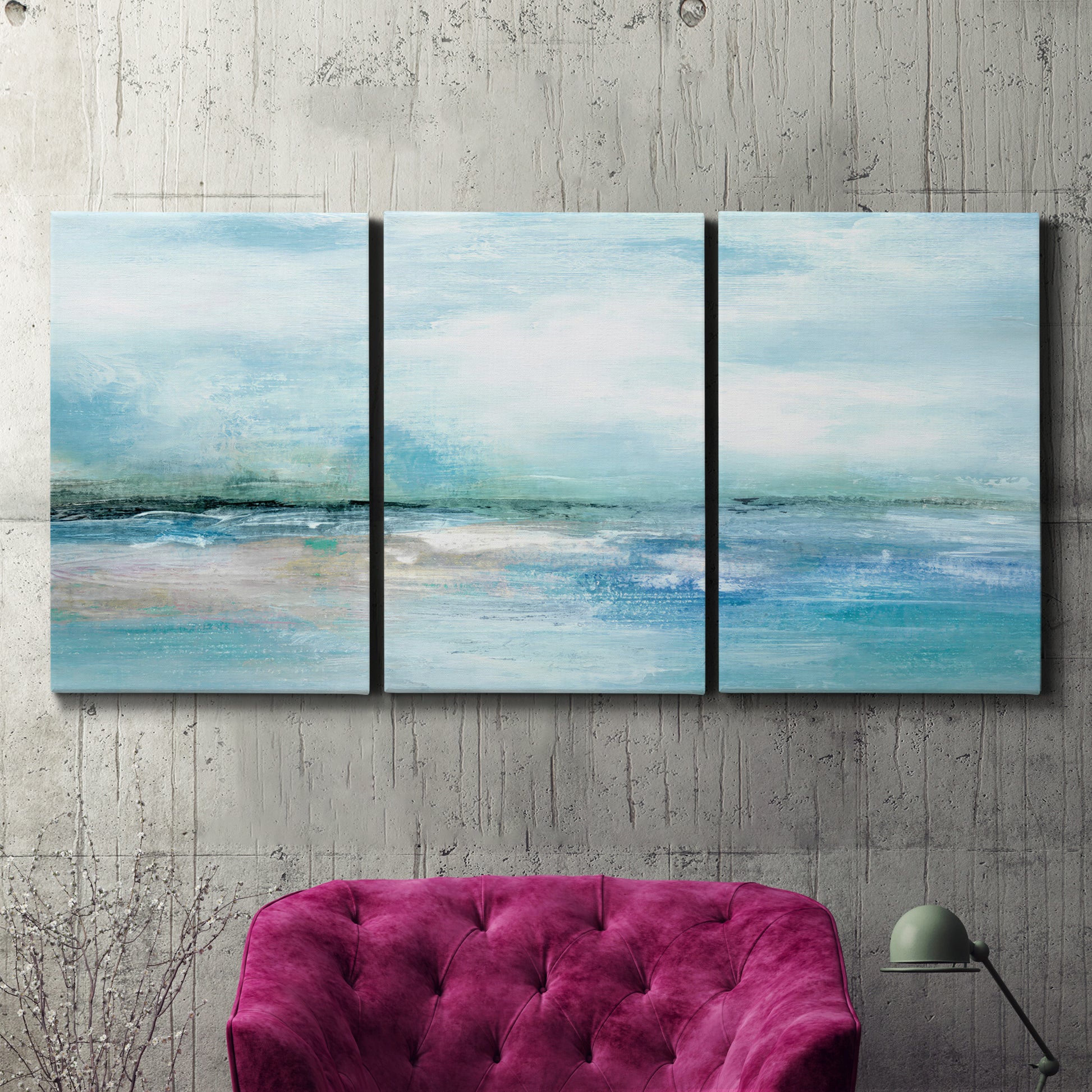 Three-panel canvas wall art featuring sunset silhouette over coastal water, displayed in a living room above a suede accent chair.