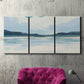 Three-panel canvas wall art featuring soft coastal shoreline landscape, displayed in a living room above a suede accent chair.