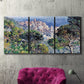 Three-panel canvas wall art featuring coastal hillside overlooking monaco, displayed in a living room above a suede accent chair.